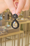 Close-up of a hand holding a diamond earring with a blurred jewelry store background.