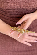 Close-up of a model holding a handcrafted gold-plated headband, showcasing an intricate cluster of shimmering amber and honey-topaz crystals shaped into delicate blossoms.