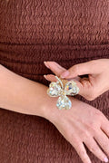 Close-up of a model holding a handcrafted gold-plated hair comb featuring a three-leaf clover design made of large, brilliant clear faceted crystals with a paved center.