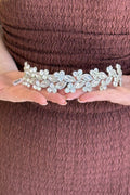 Close-up of a model holding a luxury handcrafted  heavily clustered with shimmering amber and honey-gold crystals forming textured floral patterns across a thin gold band.