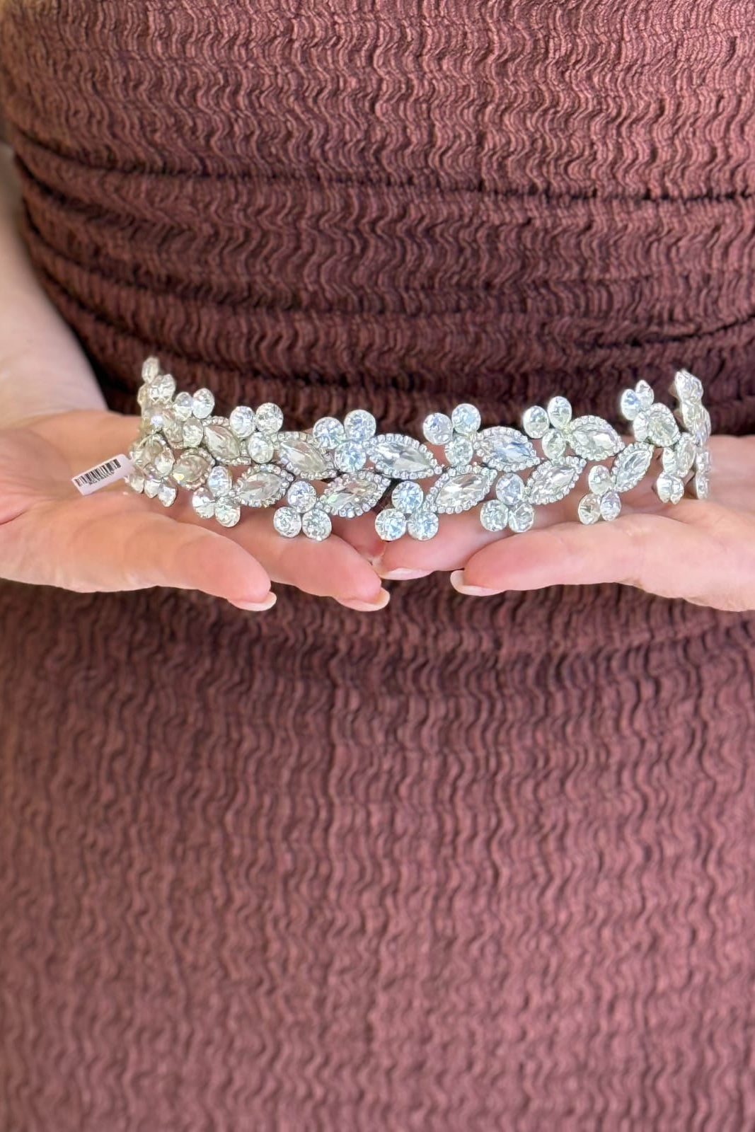 Close-up of a model holding a luxury handcrafted  heavily clustered with shimmering amber and honey-gold crystals forming textured floral patterns across a thin gold band.